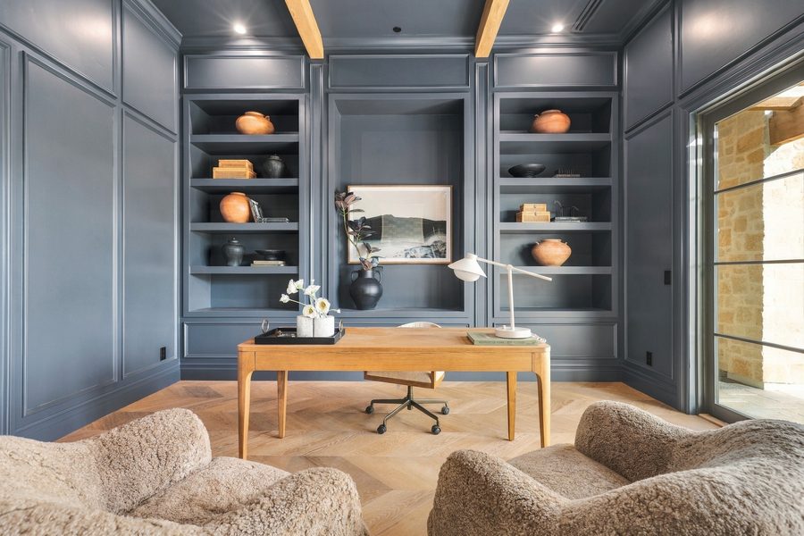 Navy-paneled office with built-in shelves and a wood desk, lit with flash