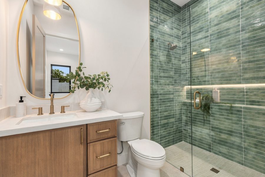 Bathroom with a green tile shower and a wood vanity