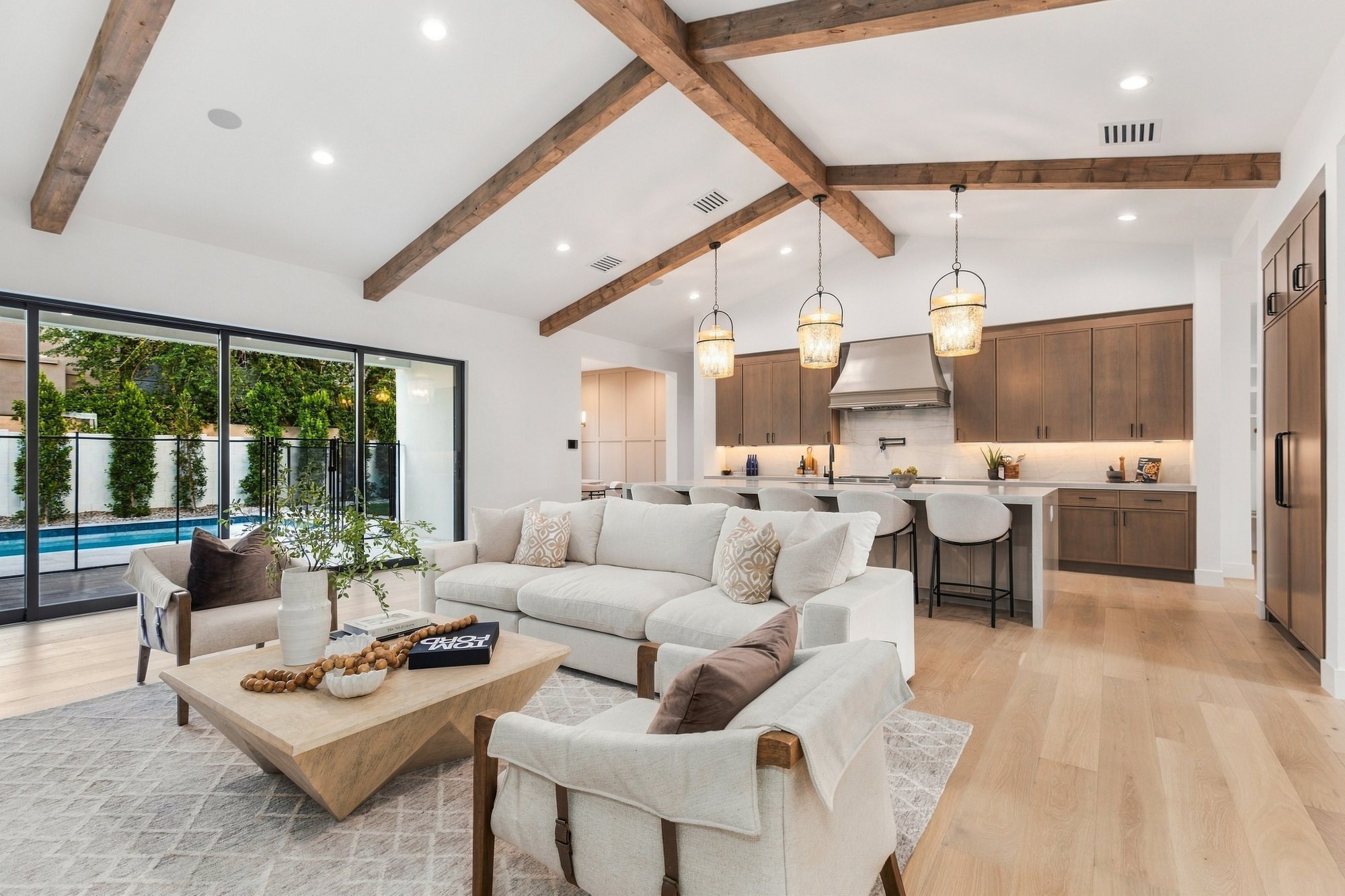 Great room under wood beams, open to the kitchen and the pool