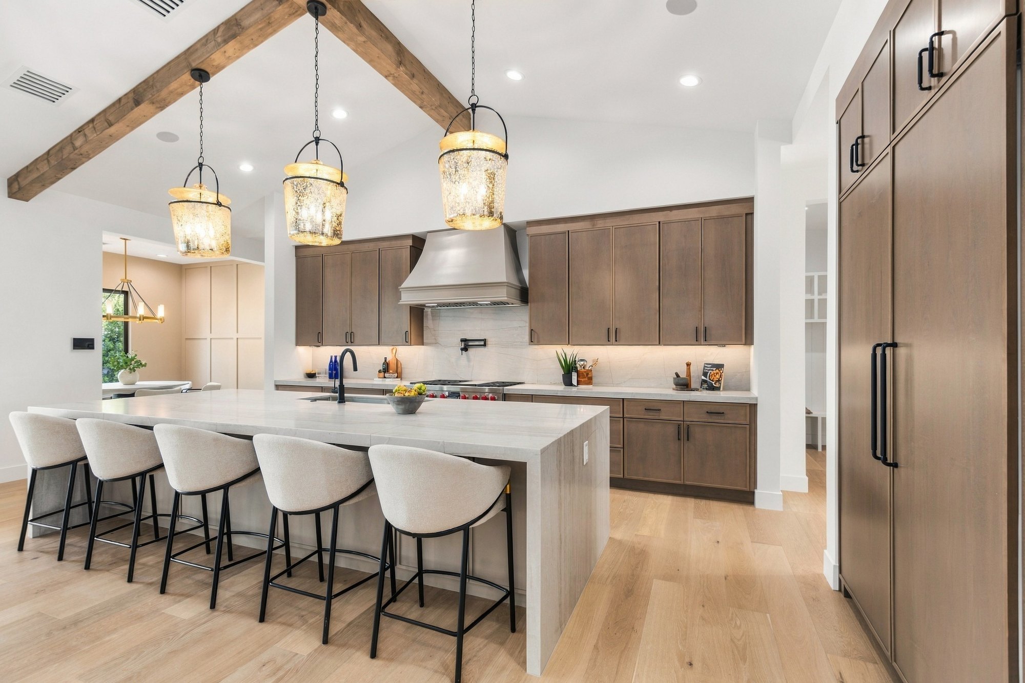Kitchen with a waterfall island, brass pendants and walnut cabinets