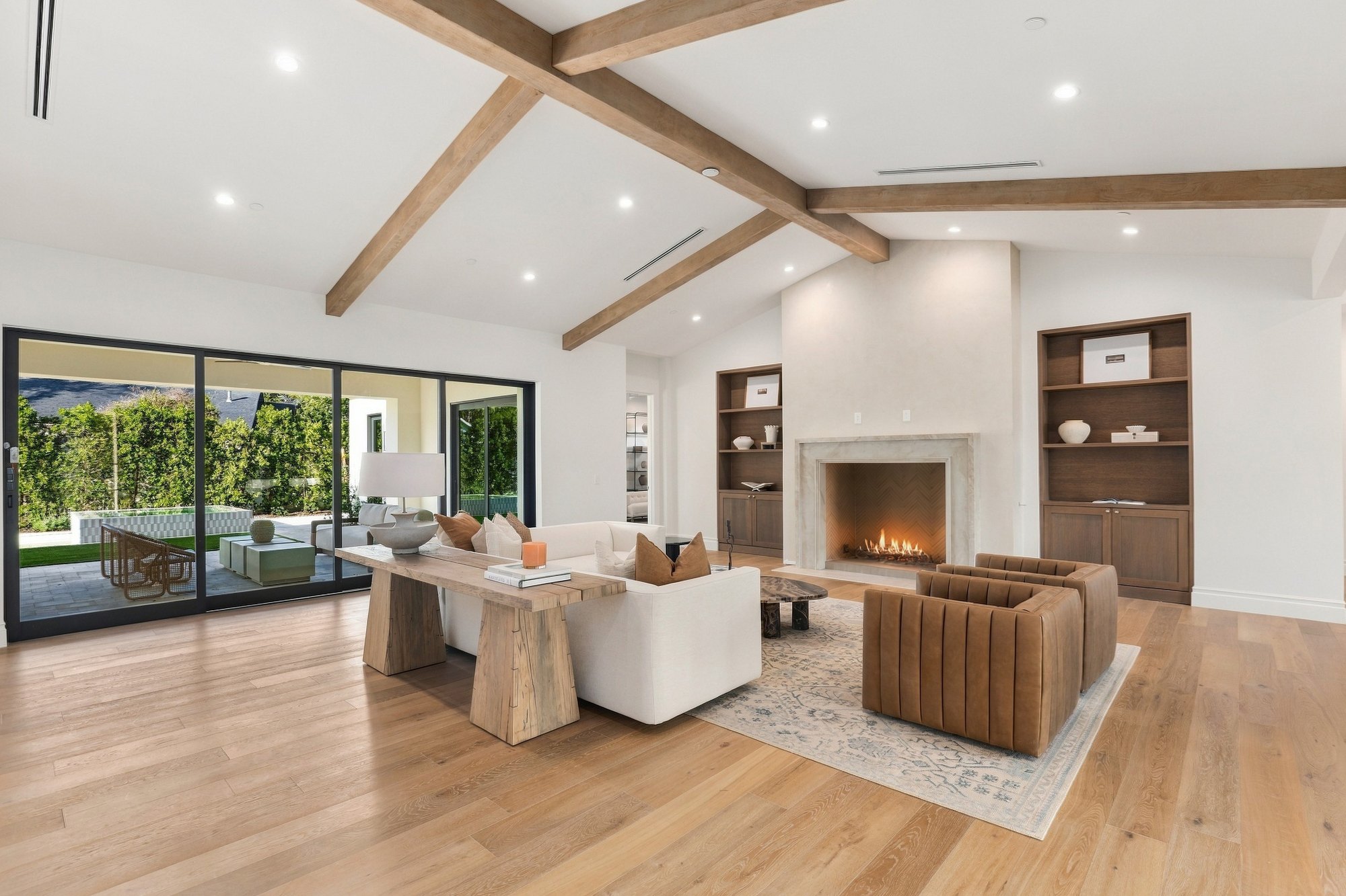 Great room with a lit fireplace under wood beams