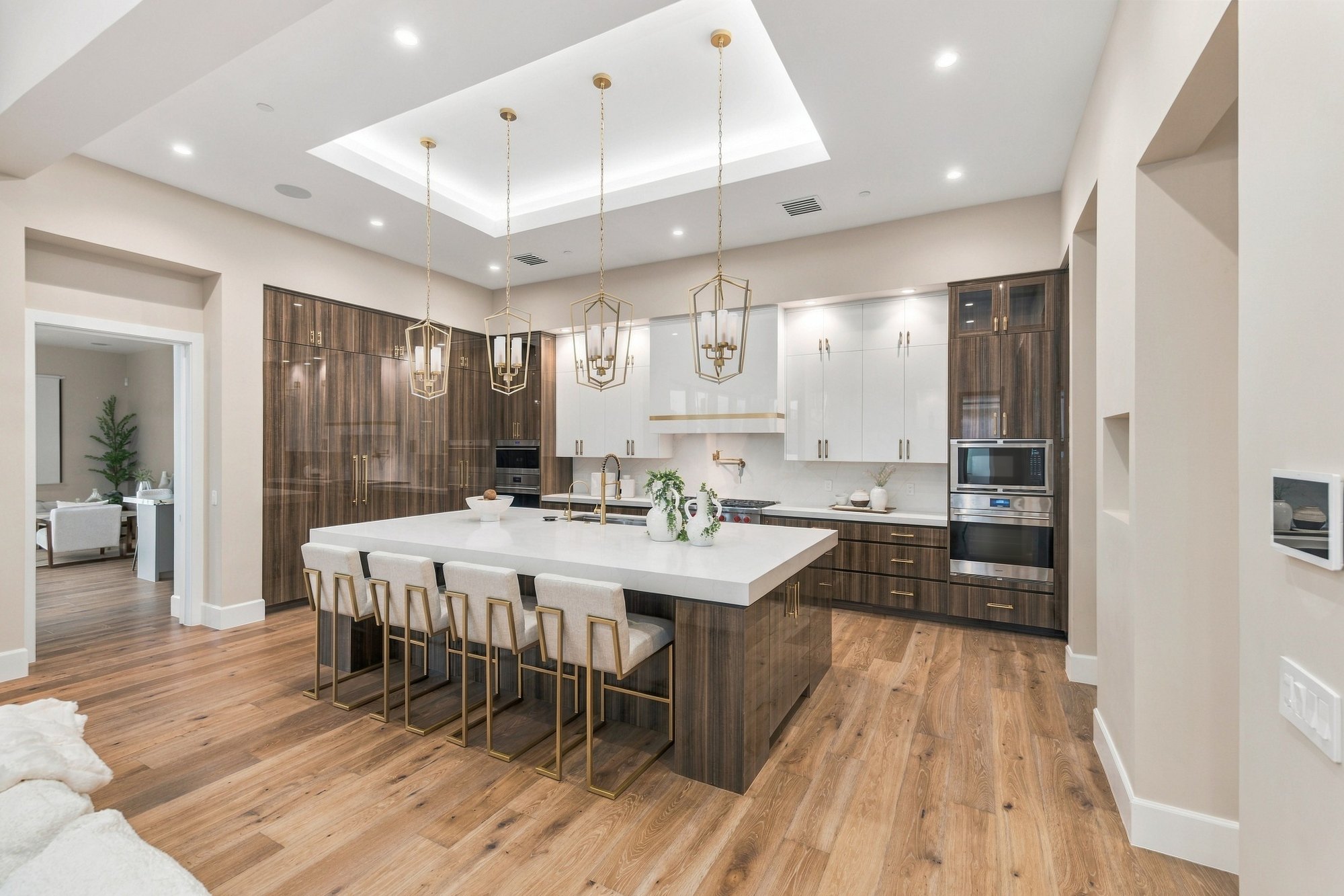 Kitchen with walnut cabinets and a white island under a lit tray ceiling